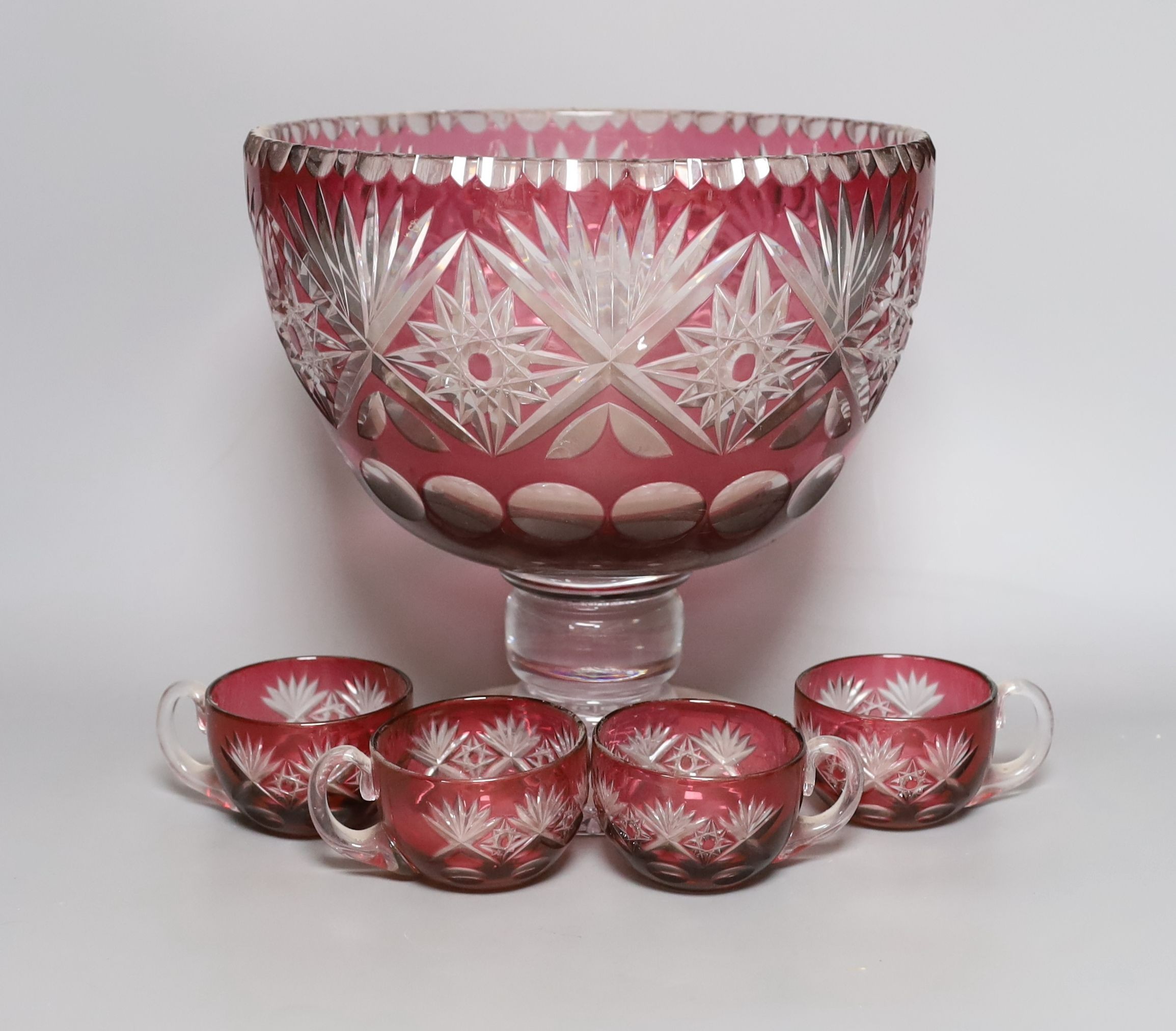 A Bohemian cut glass and cranberry overlay punch bowl with four glasses. Tallest 27cm